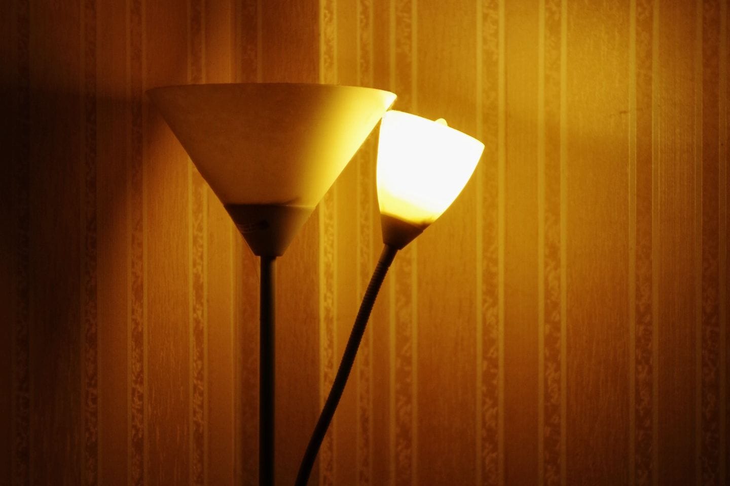 Two lit, cone-shaped lamps on a vertical stand against a patterned yellow wall, featuring low-voltage LED technology for energy-efficient lighting.