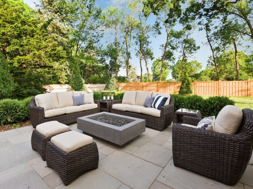 Outdoor Entertainment Spaces feature a patio with wicker furniture, beige cushions, a rectangular fire pit table, and trees framed by a wooden fence in the background.